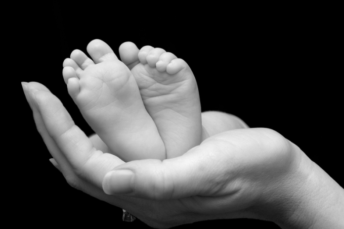 Five week old baby feet held in mothers hands.